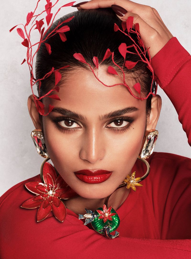 Model Bhavitha Mandava in a red leaf headpiece, glossy red lipstick, and ornate floral statement jewelry.