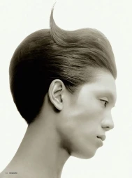 Profile portrait of a male model with sculpted dark hair and a curved lock against a plain white background for Vogue Man Philippines.