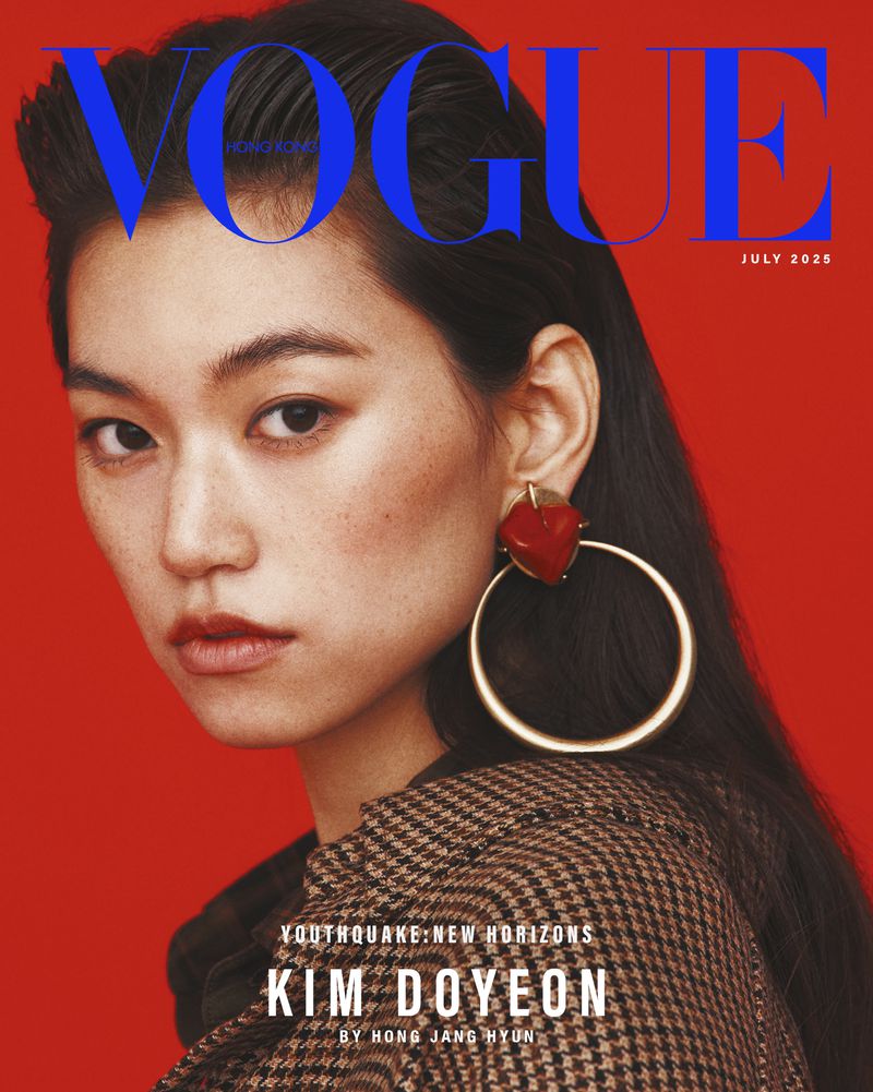 Vogue magazine cover featuring an Asian woman with dark hair, wearing a brown checkered coat and hoop earrings, against a red background.