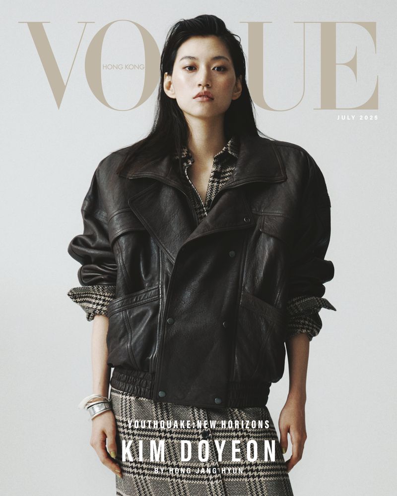 Vogue Hong Kong cover featuring Kim Doyeon, full-length shot in a dark leather jacket and plaid skirt against a bright background.