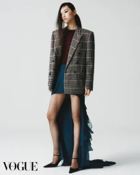 Model in houndstooth blazer and layered teal gown against a white background for Vogue Hong Kong.