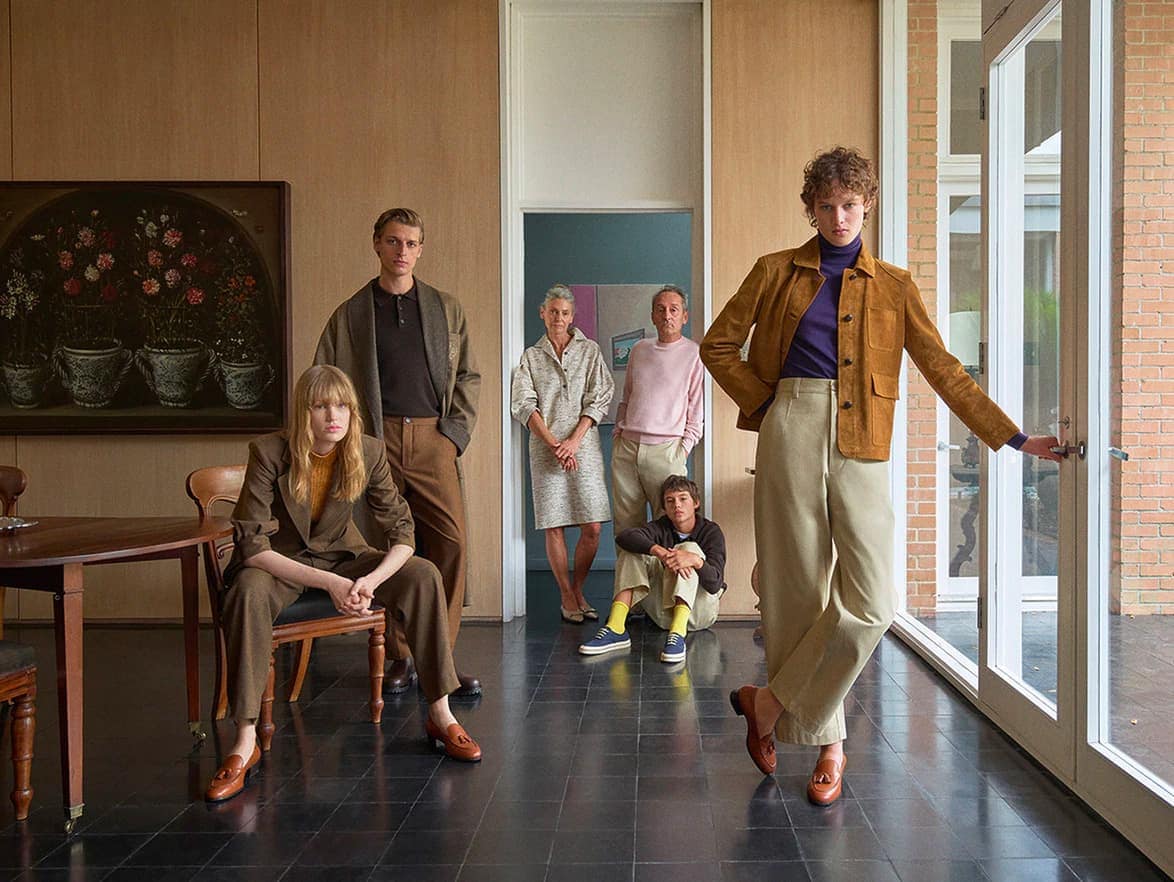 Group of fashion models posing in an elegant interior wearing suede jackets, knitwear, and tailored trousers.