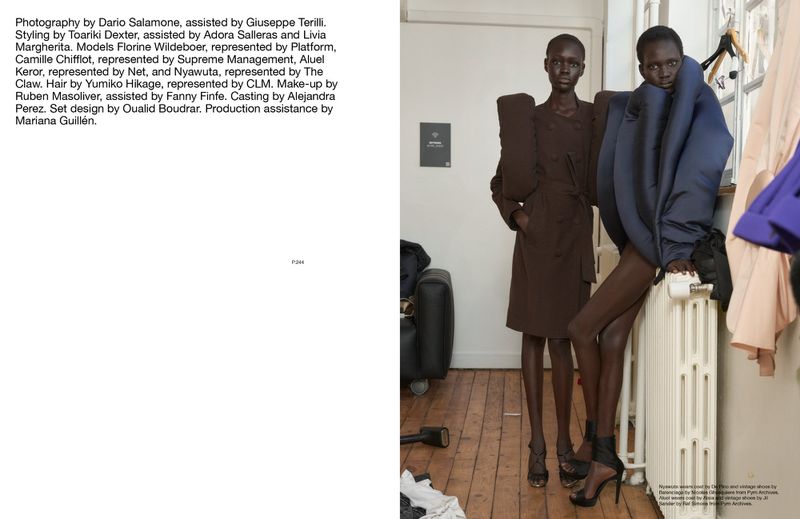 Two black female fashion models in oversized designer clothing pose indoors against a white radiator and wall in a fashion editorial.