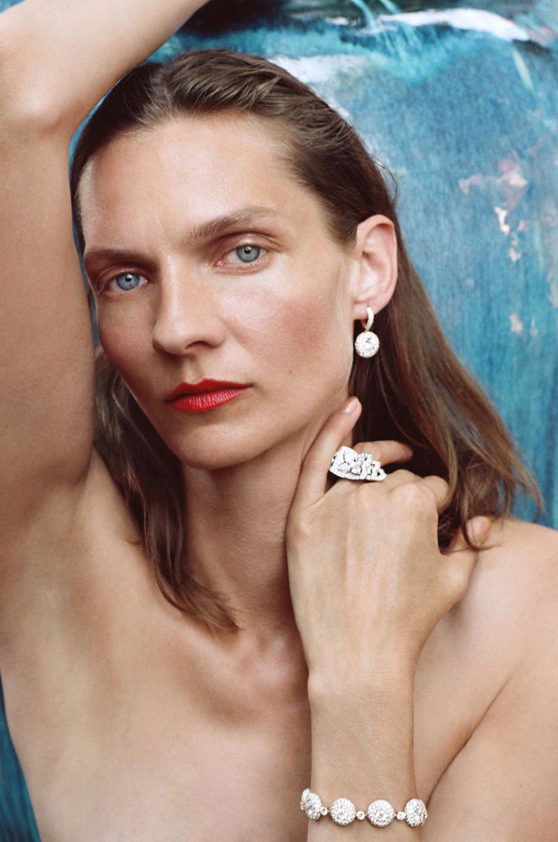 Model Karolin Wolter wearing diamond jewelry with red lipstick against a textured blue backdrop for Coeur de pierres.