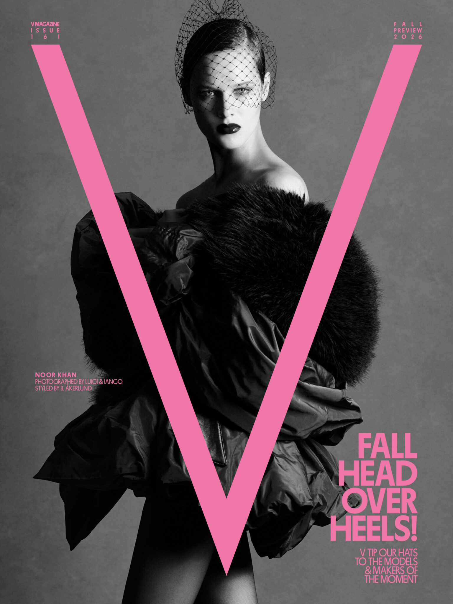 Model Noor Khan wearing a voluminous black ruffled coat and mesh veil on a black and white cover of V Magazine with pink typography.