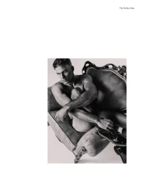 Monochrome editorial portrait of a shirtless man seated curled in an ornate vintage armchair wearing black patent shoes.