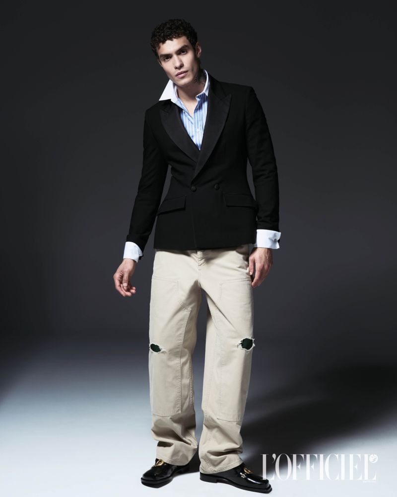 Model Leandro da Silva wearing a tailored black blazer and distressed beige trousers for L'Officiel Hommes Italia.