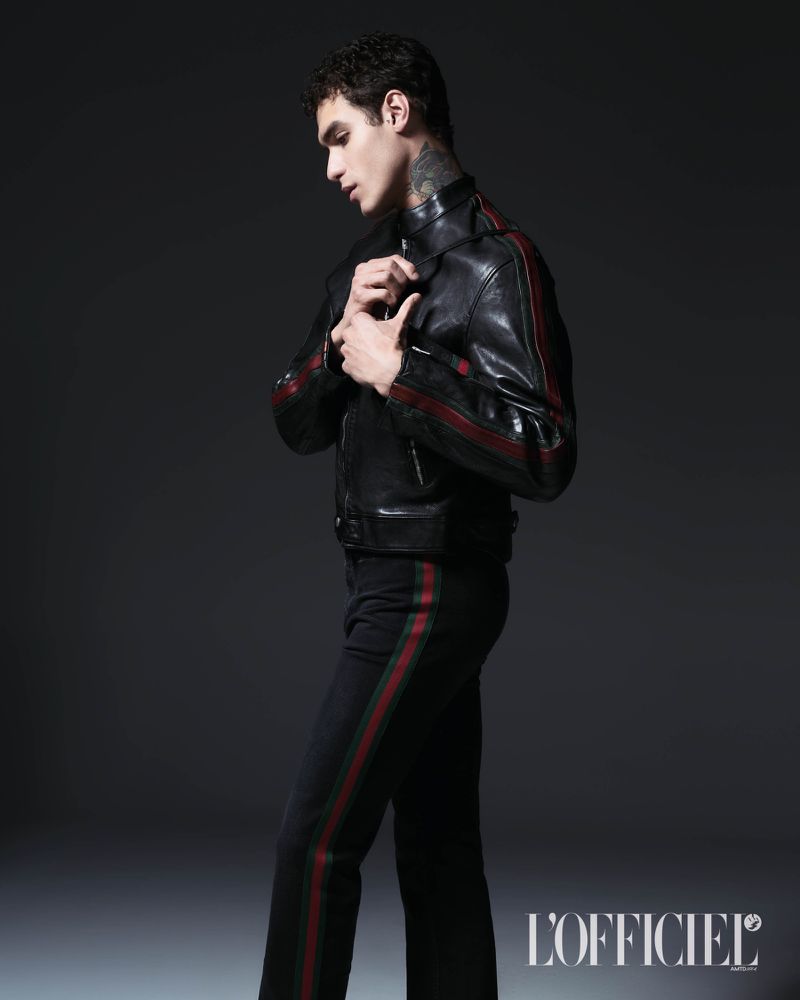 Model Leandro da Silva in a black leather striped jacket and matching trousers against a dark studio background.