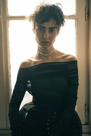 Model Lando van der Schee wearing a sheer off-the-shoulder black top and sparkling choker in front of a bright window.