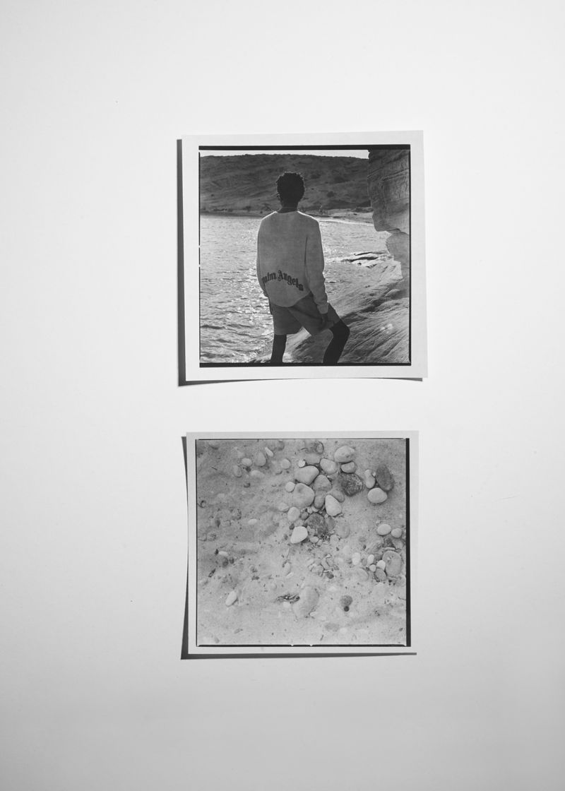 Two black-and-white photographs: one of a person looking at the ocean, and one of sandy ground with pebbles, presented as a diptych.