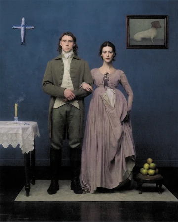 Daisy Edgar-Jones and male model posing in period costumes against a deep blue studio wall with classical props.