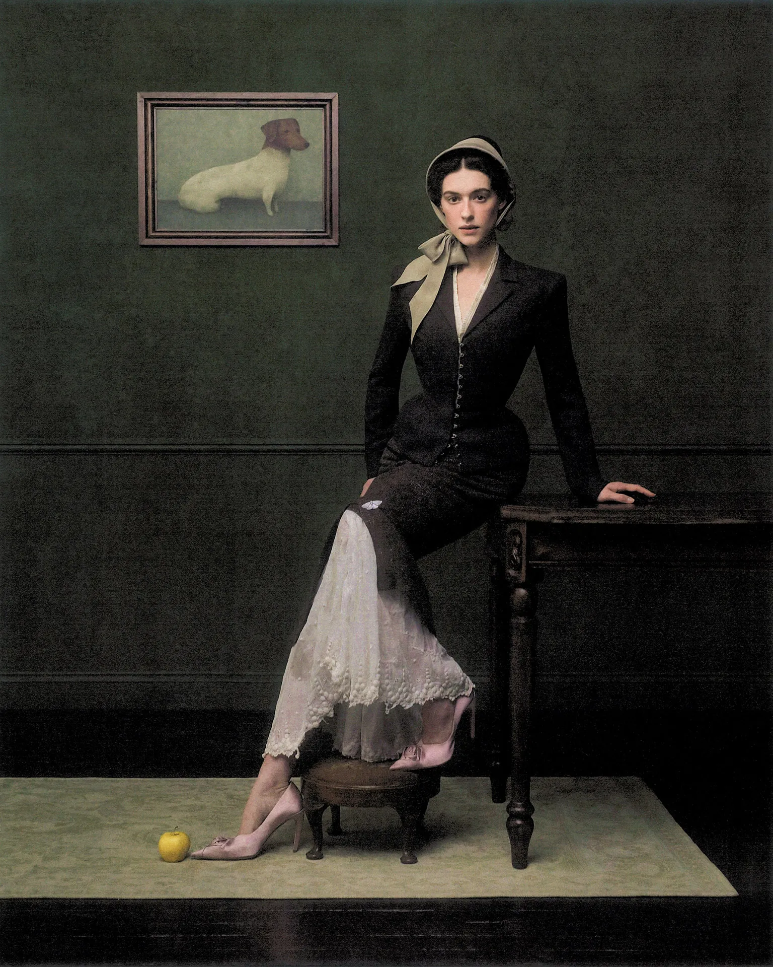 Daisy Edgar-Jones in a dark tailored jacket and lace skirt with bonnet, seated beside a table in a green room with dog painting.