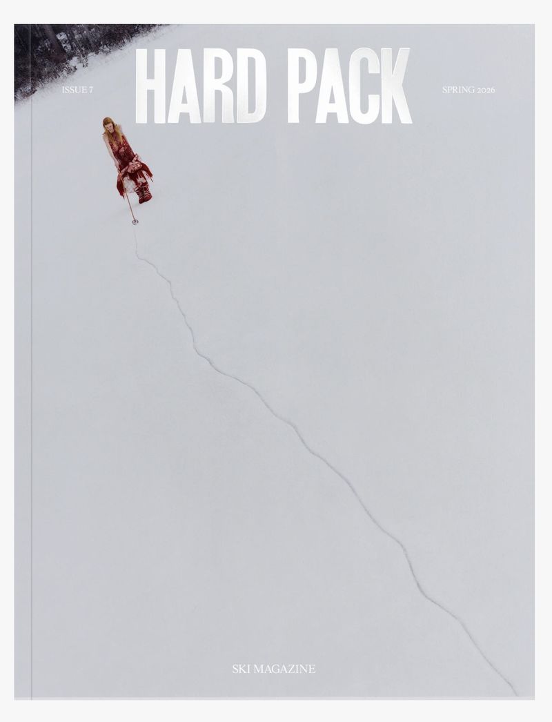 Magazine cover showing a person in a red patterned outfit walking across a vast white snowfield leaving a single winding trail.