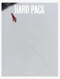 Magazine cover showing a person in a red patterned outfit walking across a vast white snowfield leaving a single winding trail.