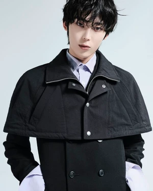 Young man wearing a black collared coat over a light purple shirt against a white background