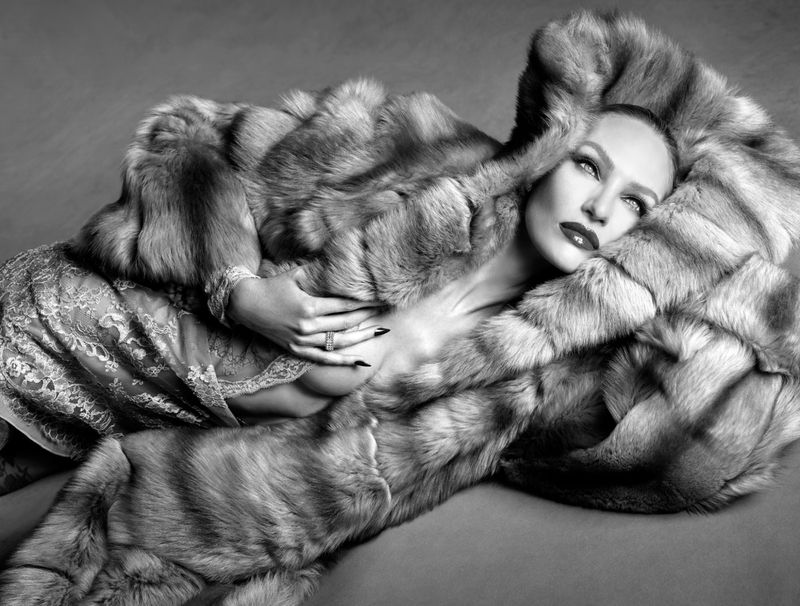 Monochrome portrait of Candice Swanepoel reclining in a voluminous fur coat and lace lingerie.