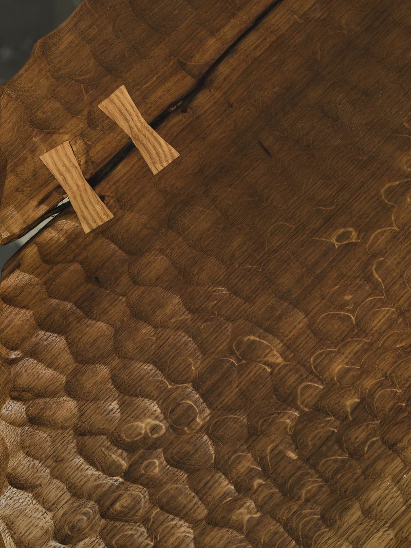 Close-up of hand-carved textured timber with two wooden butterfly joint keys set across a fissure.