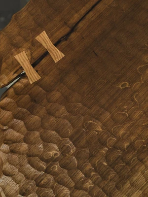 Close-up of hand-carved textured timber with two wooden butterfly joint keys set across a fissure.