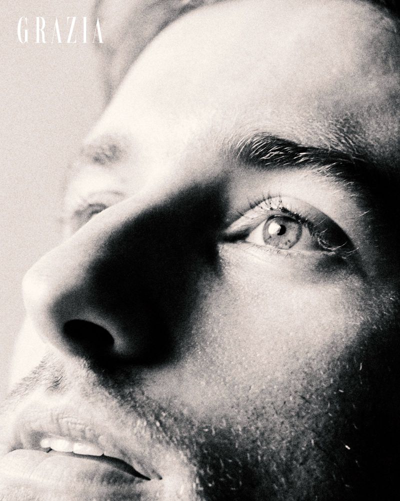 Monochrome close-up portrait of a man looking upward, highlighting his eye, nose, and facial stubble under directional light.