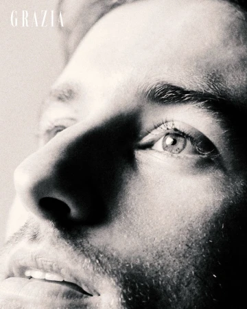 Monochrome close-up portrait of a man looking upward, highlighting his eye, nose, and facial stubble under directional light.
