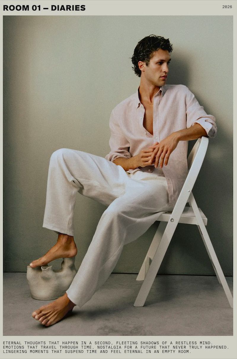 Model Francisco Henriques seated barefoot on a white chair wearing a pink linen shirt and white trousers for Massimo Dutti.