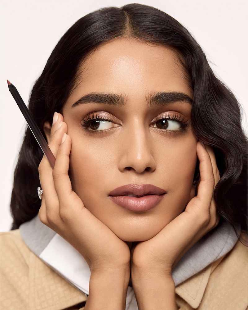 Model Mahi Kabra holding a makeup pencil to her face in a beauty portrait for Louis Vuitton Crayon with makeup by Pat McGrath.