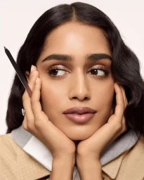 Model Mahi Kabra holding a makeup pencil to her face in a beauty portrait for Louis Vuitton Crayon with makeup by Pat McGrath.