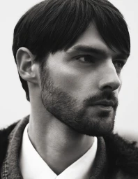 Monochrome close-up portrait of model Hannes Gobeyn looking to the side wearing a collared shirt and textured jacket.