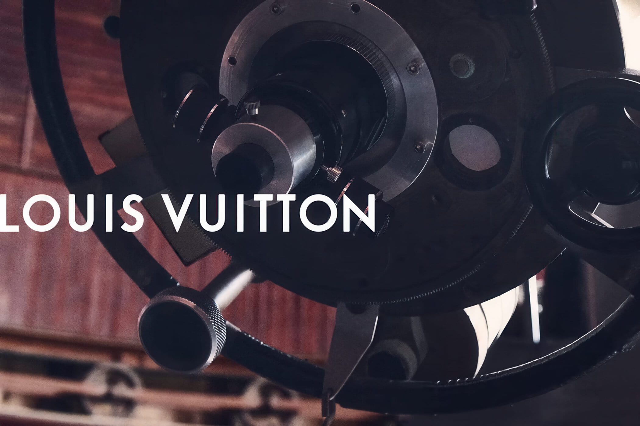 Astronomical telescope mechanism and eyepiece with white Louis Vuitton typography overlay.