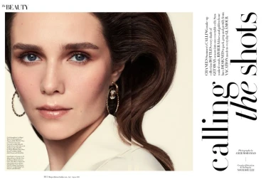 Beauty editorial portrait of a woman with styled voluminous brown hair and gold hoop earrings across a magazine layout.