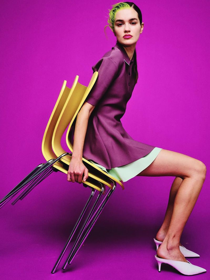 Model Amélie Auger posing on stacked yellow chairs against a magenta background for Numero Tokyo, photographed by Pakbae.