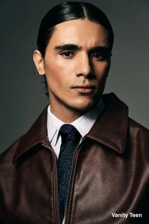 Model Kamal Sad wearing a dark brown leather jacket, striped shirt, and patterned tie against a grey studio backdrop for Vanity Teen.