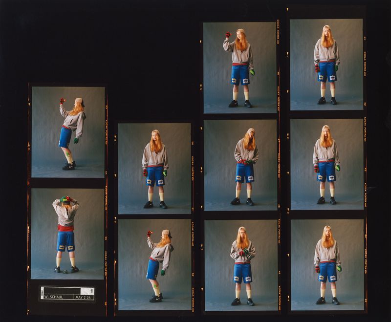 Film contact sheet of a long-haired model in a grey hoodie and blue athletic shorts posing against a grey studio backdrop.