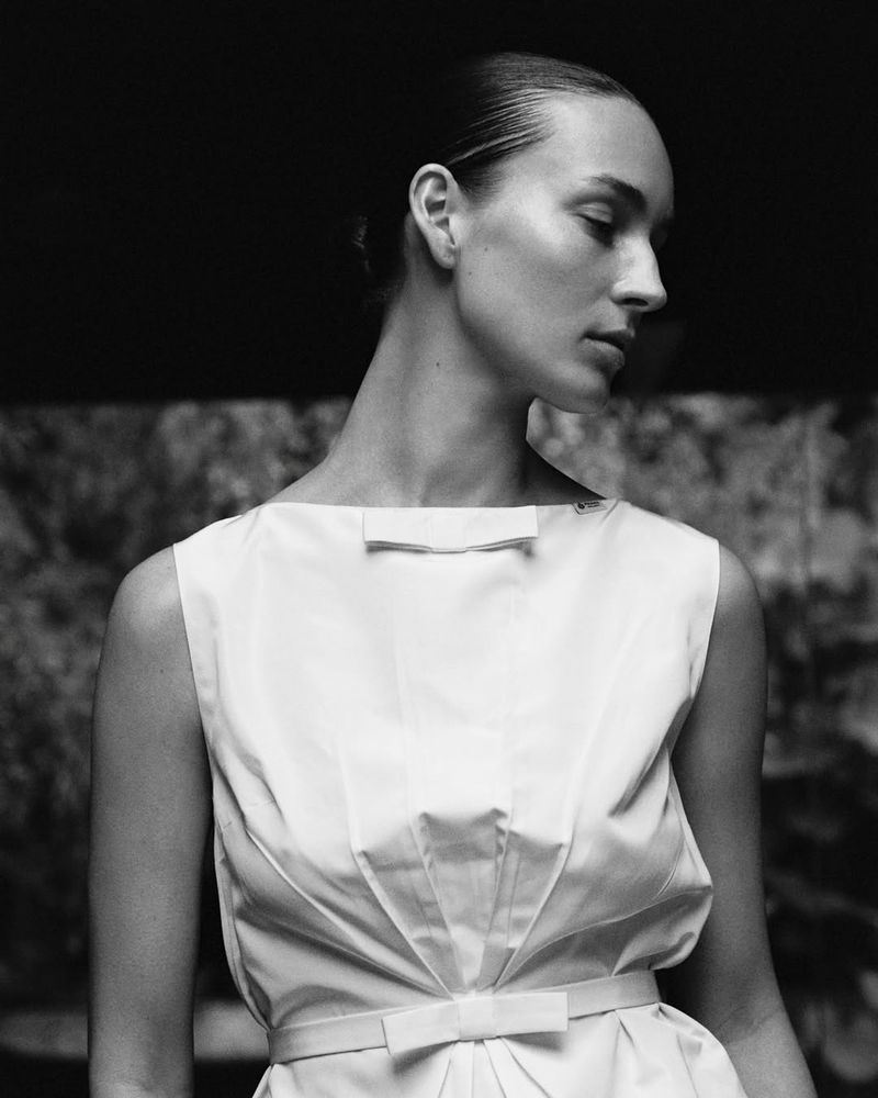 Monochrome portrait of model Julia Bergshoeff looking down, wearing a structured white sleeveless top with bow details.