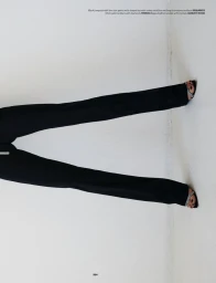Lower body crop of model wearing black tailored wide-leg trousers and glittering strap heels against a white studio wall.