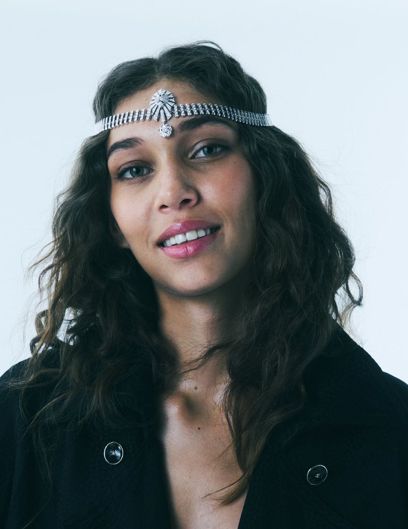 Model Latahlia Hickling wearing a sparkling crystal headpiece and black jacket against a white studio background.