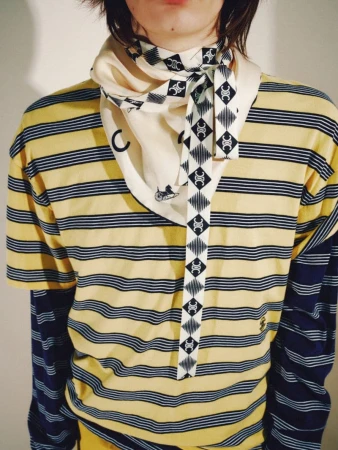 Model wearing a yellow striped t-shirt layered over long sleeves and a patterned Celine silk scarf tied at the neck.