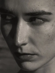 Close-up portrait of a model with dark eyebrows and freckles lit by directional light for the Merlette Pre Fall 2025 campaign
