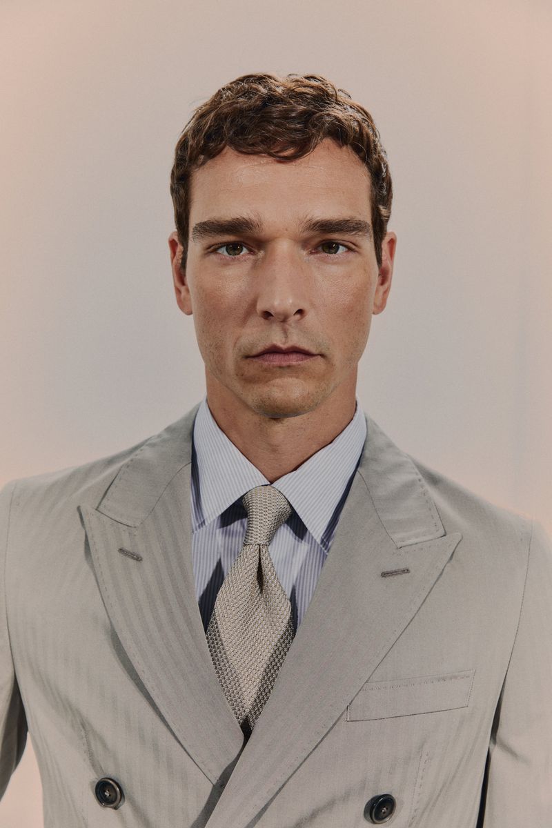 Portrait of a handsome adult man in a light-colored suit, dress shirt, and tie against a light backdrop for fashion or business use.