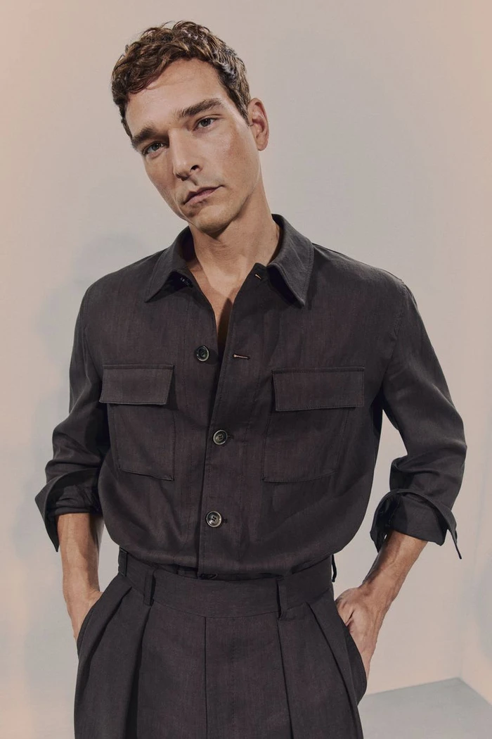 Model Alexandre Cunha wearing a dark grey button-down shirt and trousers against a neutral studio backdrop for BOSS.
