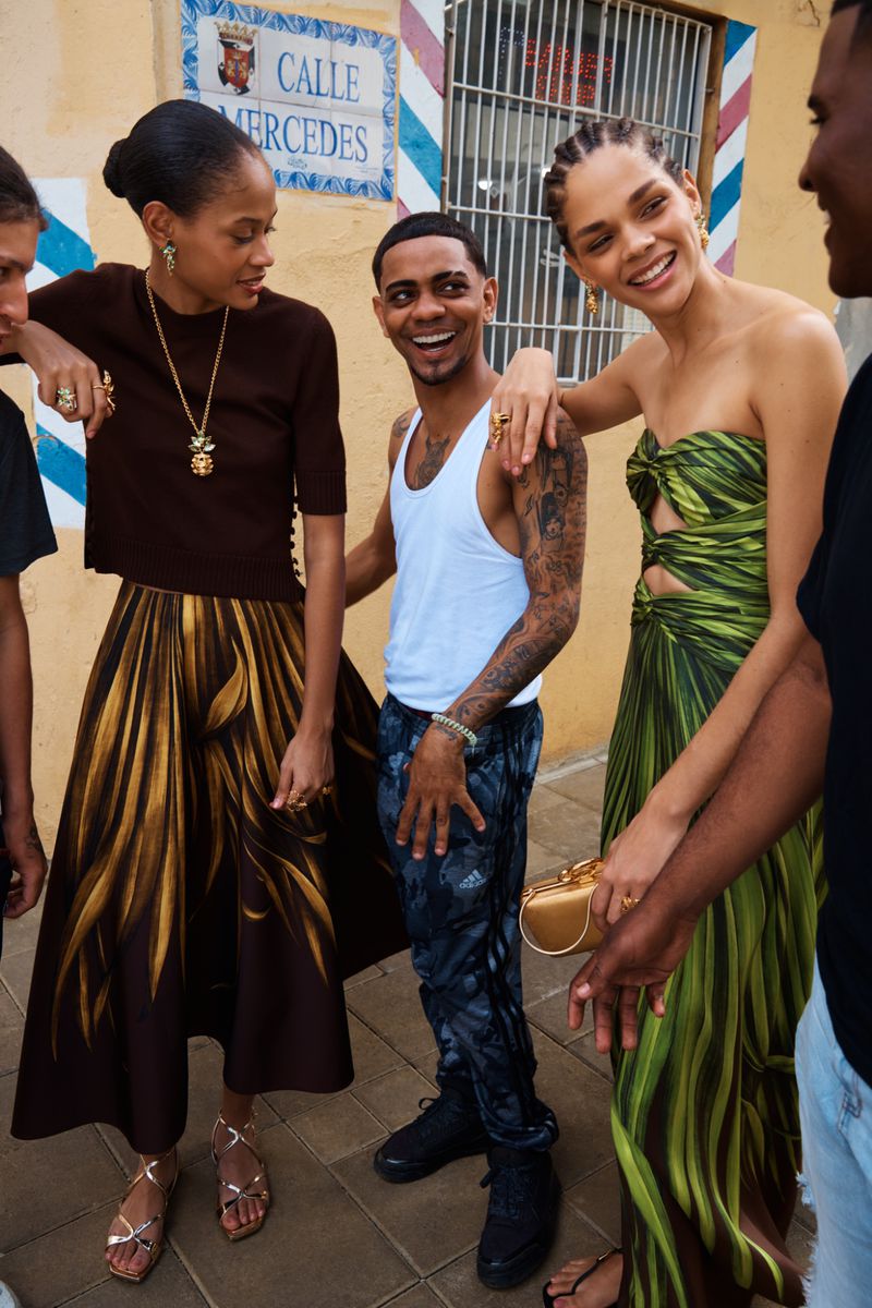 Group of models posing outdoors on a street by a yellow wall for Oscar de la Renta Pre-Fall 2026 collection by Brett Warren
