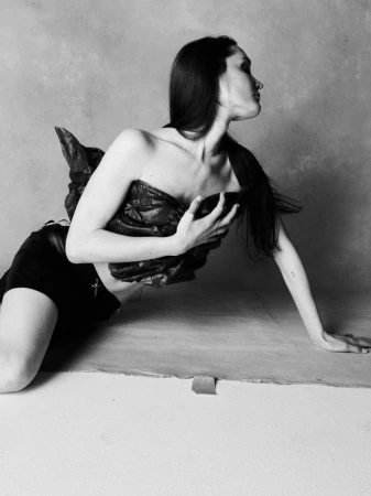 Model Jules Santiago reclining on a studio floor wearing a sculpted strapless top for SLIMI Magazine's The Revival Issue.