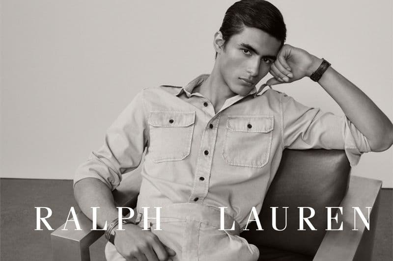 Model Mathieu Simoneau seated in a modern armchair wearing a button-up utility shirt in a black and white Ralph Lauren portrait.