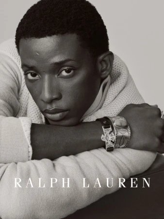 Black and white portrait of a Black man in a knit sweater and silver cuffs looking at the camera for Ralph Lauren.