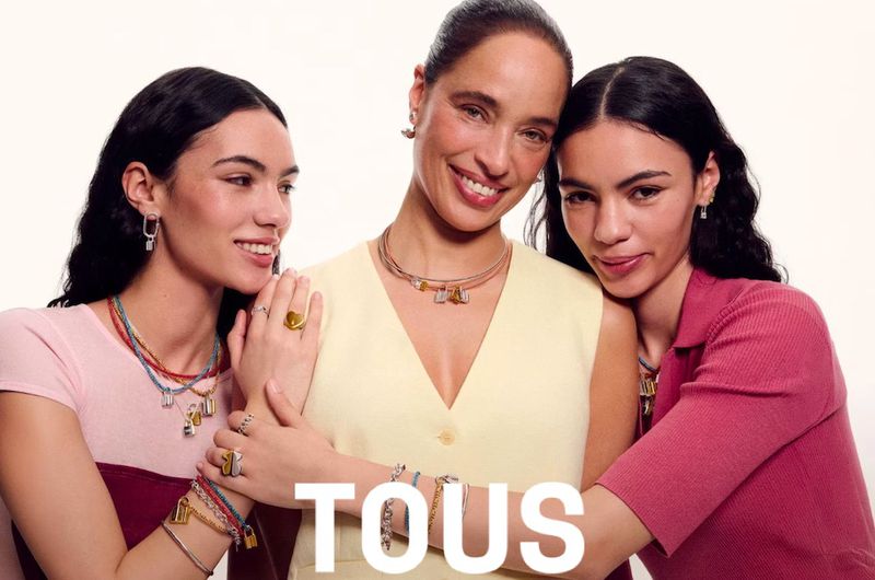 Three female models posing together wearing layered necklaces and rings against a plain light background for Tous