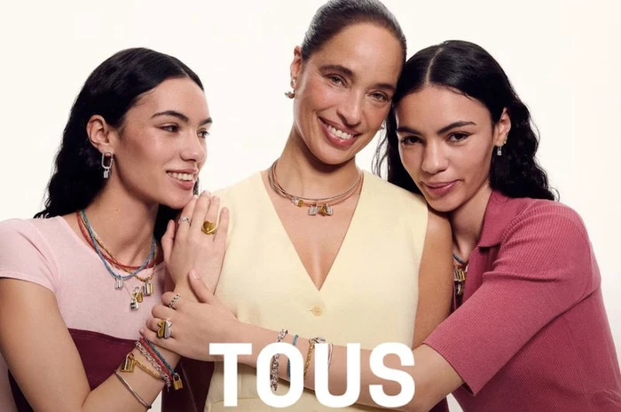 Three female models posing together wearing layered necklaces and rings against a plain light background for Tous