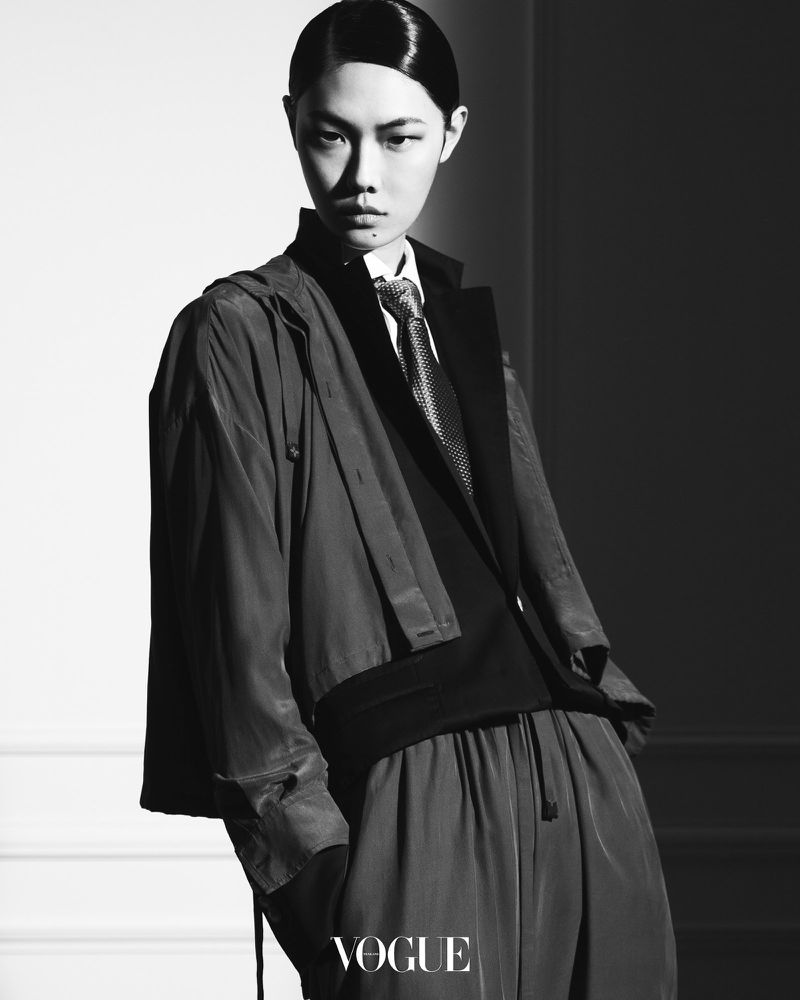 Model Sijia Kang wearing tailored outerwear and tie in a high-contrast black and white editorial photograph for Vogue Thailand.