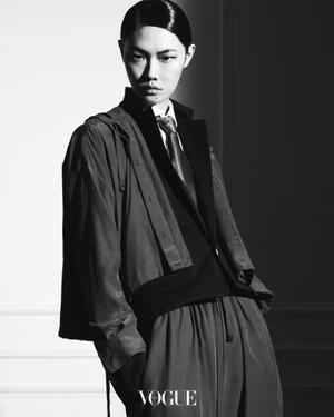 Model Sijia Kang wearing tailored outerwear and tie in a high-contrast black and white editorial photograph for Vogue Thailand.
