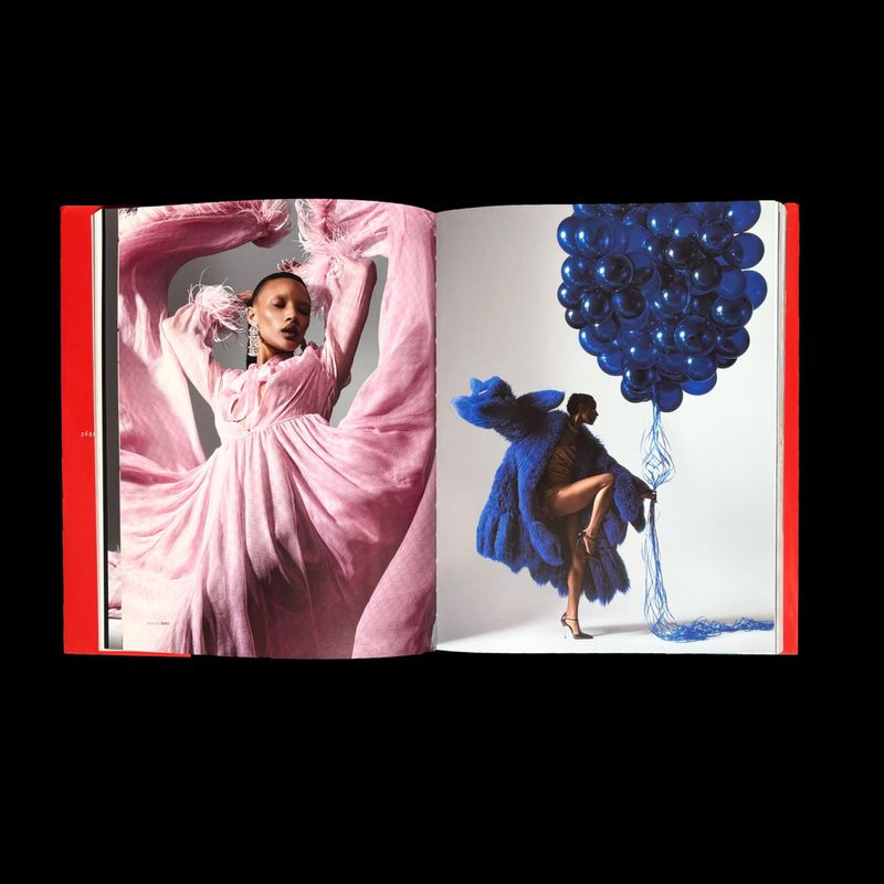 Open magazine showing editorial fashion pages with a model in a pink dress and a model holding blue balloons