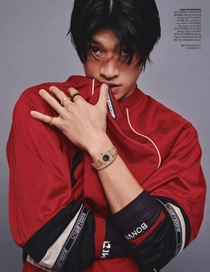 Model Woohyeong Jang pulling collar of a red sports jersey to his mouth while wearing a gold watch for Harper's Bazaar Korea.